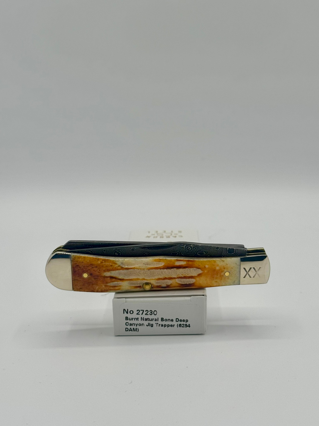 Case XX 27230 Damascus Burnt Natural Bone Deep Canyon Jig Trapper — lifestyle angle on Case box