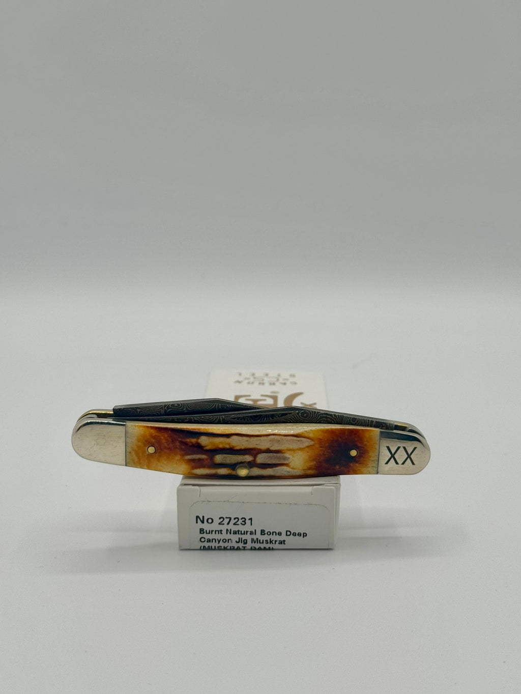Case XX 27231 Damascus Burnt Natural Bone Deep Canyon Jig Muskrat — lifestyle angle on Case box