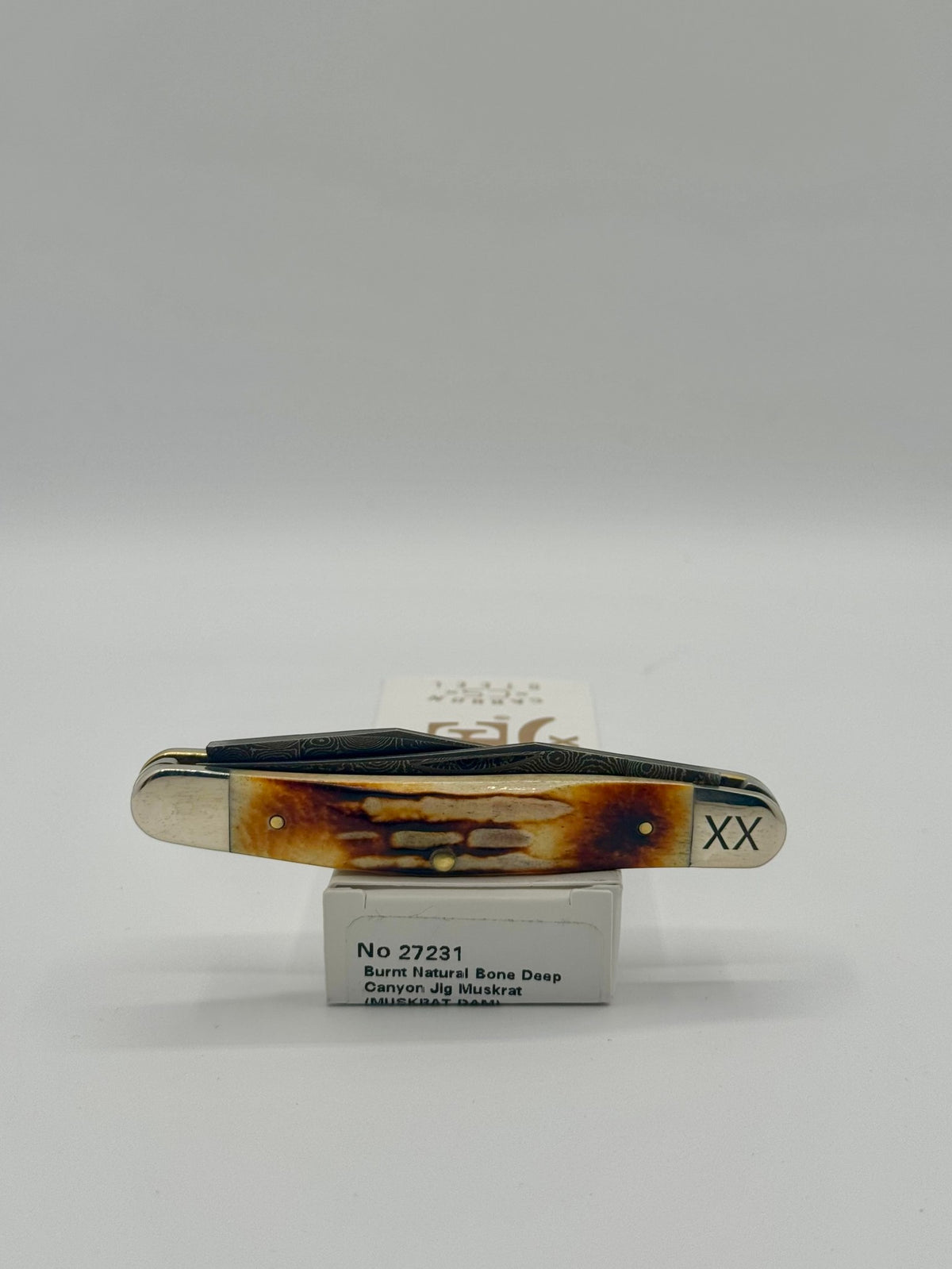 Case XX 27231 Damascus Burnt Natural Bone Deep Canyon Jig Muskrat — lifestyle angle on Case box