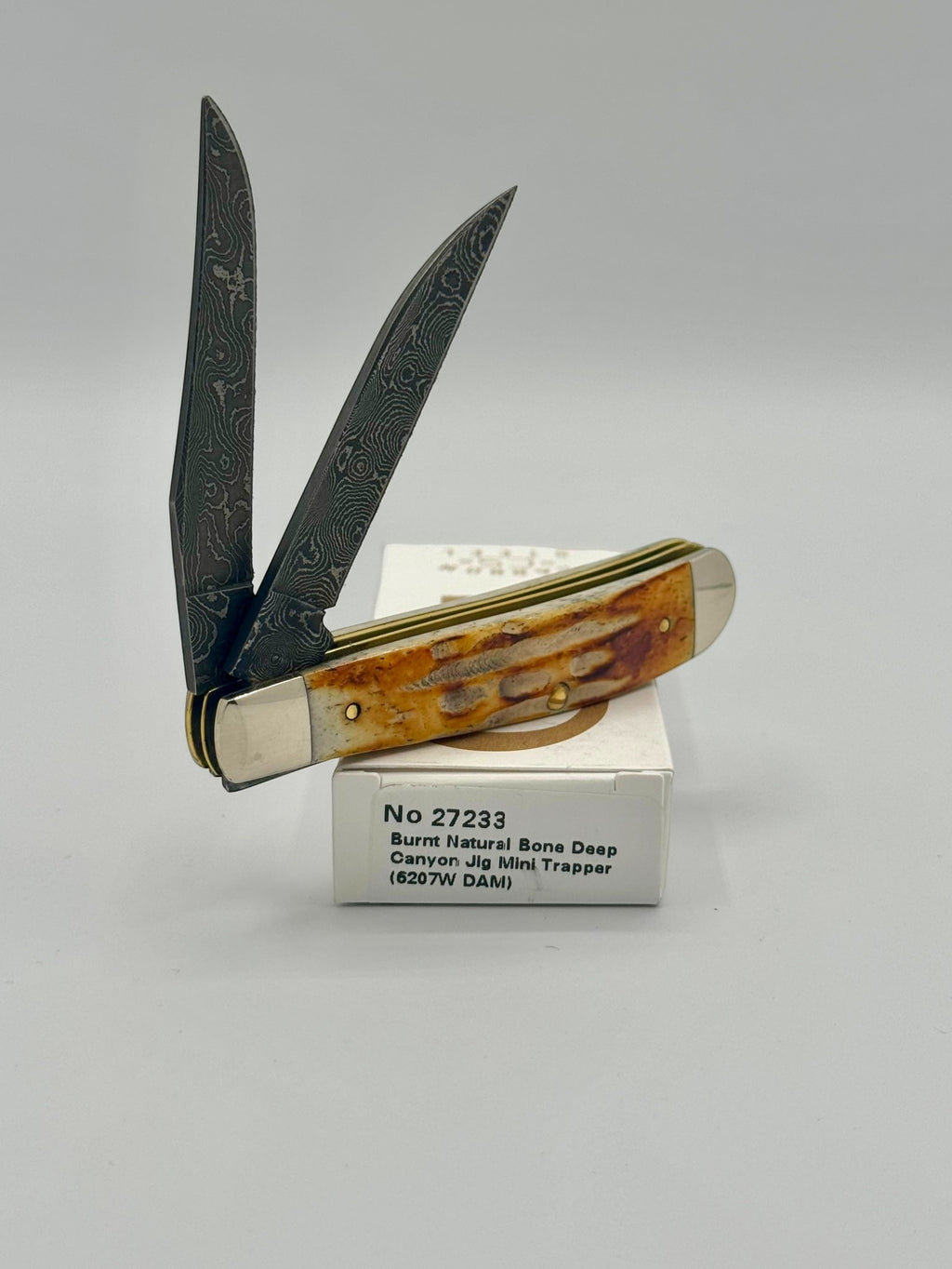 Case XX 27233 Damascus Burnt Natural Bone Deep Canyon Jig Mini Trapper — back side on Case box