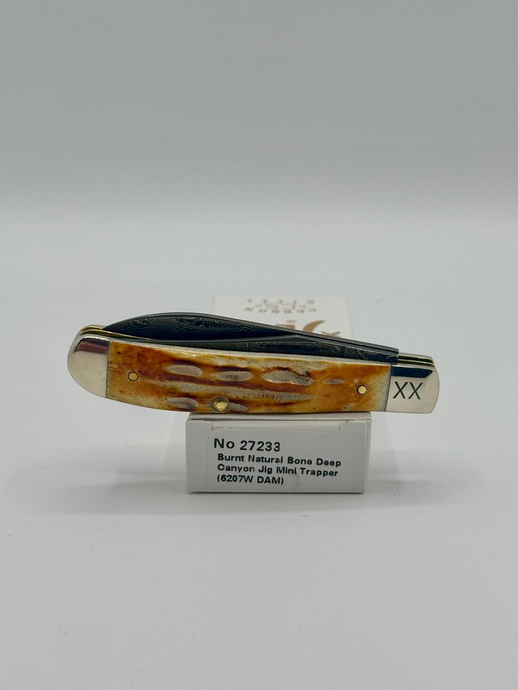Case XX 27233 Damascus Burnt Natural Bone Deep Canyon Jig Mini Trapper — lifestyle angle on Case box