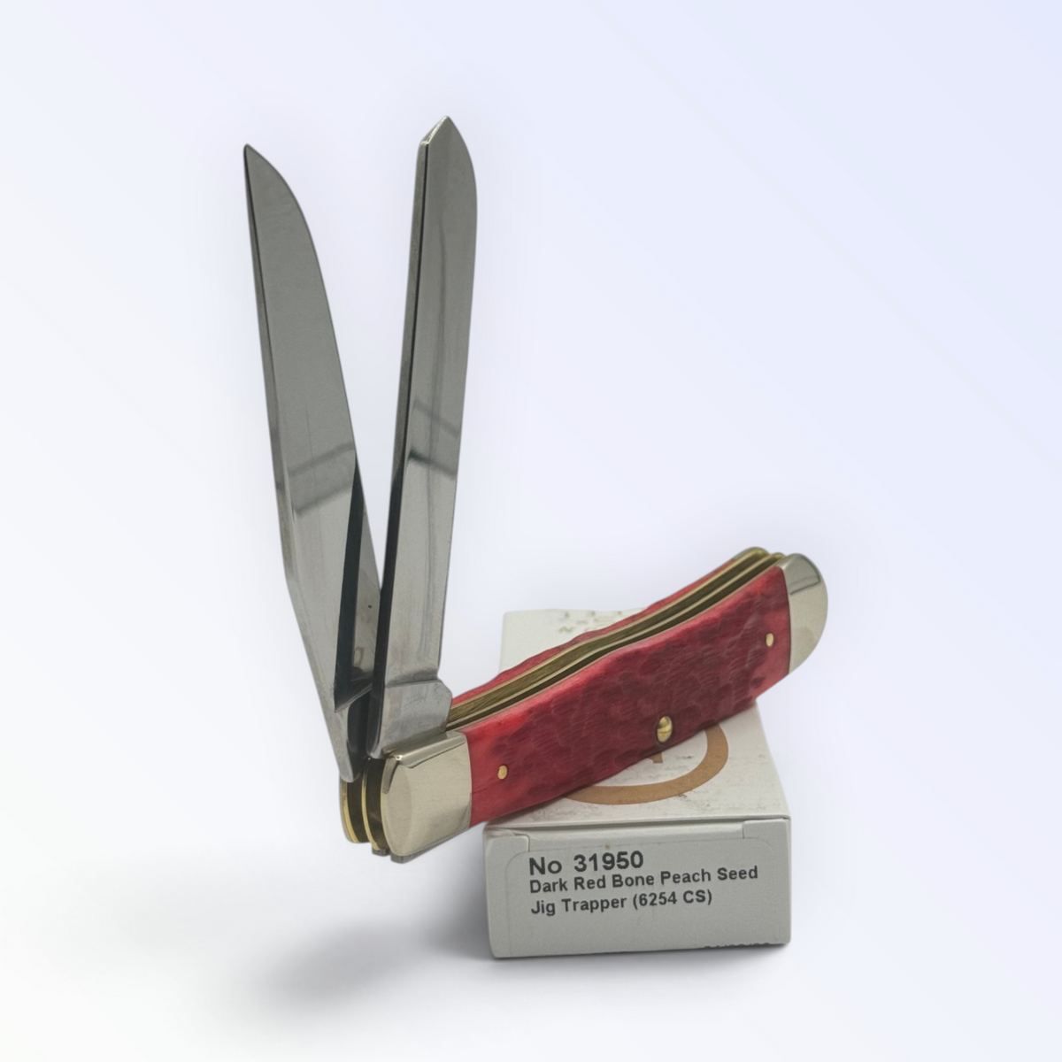 Case XX – Dark Red Bone Peach Seed Jig Trapper (31950) — pocket-knife studio shot on retail box