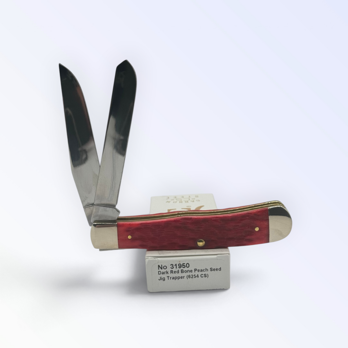 – Dark Red Bone Peach Seed Jig Trapper by Case XX (31950), close view of handle texture with blades open on box