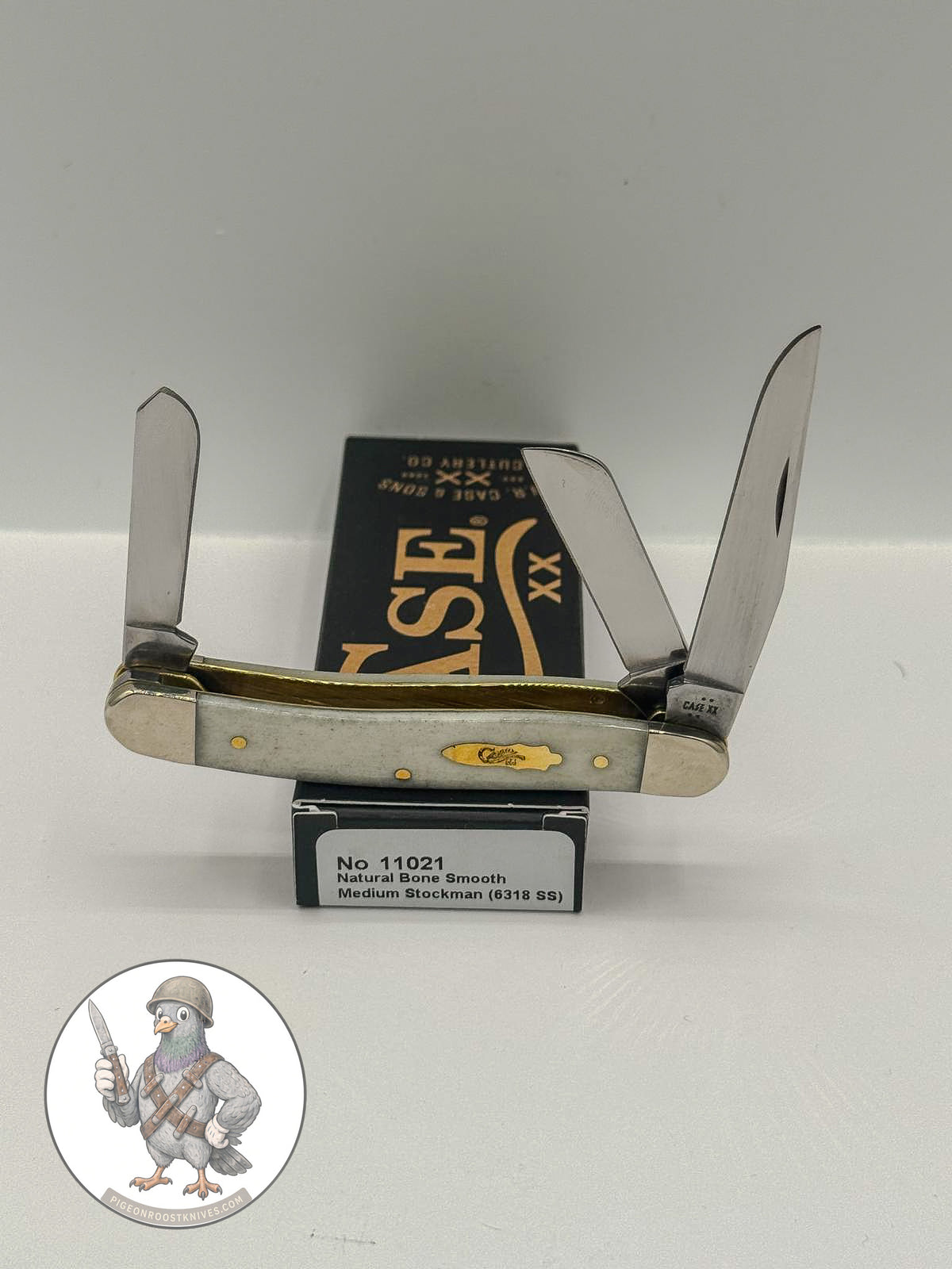 Case XX Medium Stockman with smooth natural bone and three stainless blades, SKU 11021 — blades open resting on the factory box