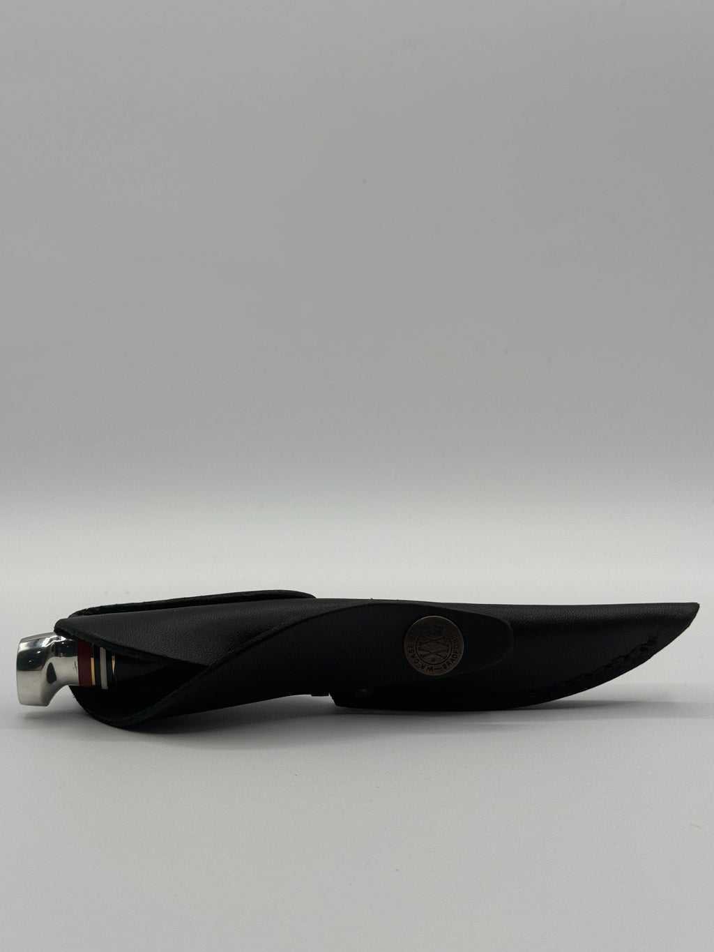 Pigeon Roost Knives Case XX Mini Finn fixed blade knife inside a black leather sheath with a branded metal snap