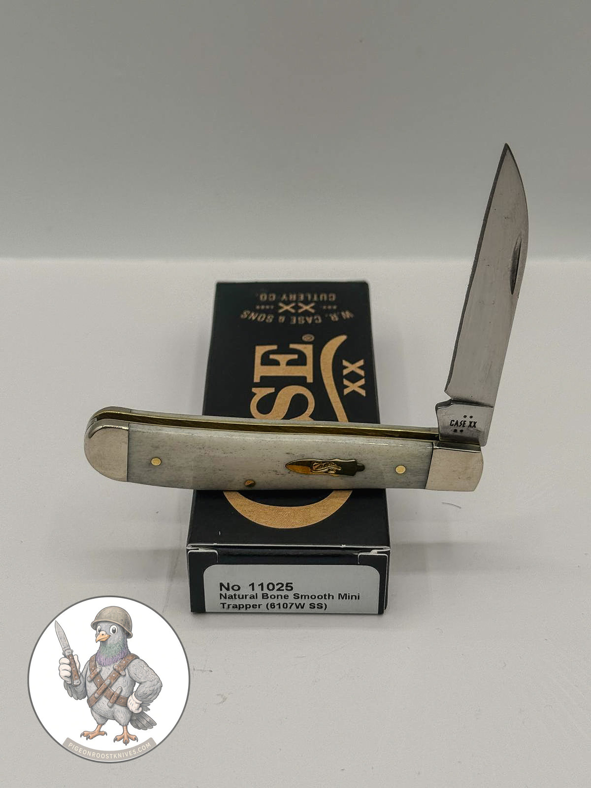 Case XX Mini Trapper with smooth natural bone and Wharncliffe and spey blades, SKU 11025 — blades open resting on the factory box