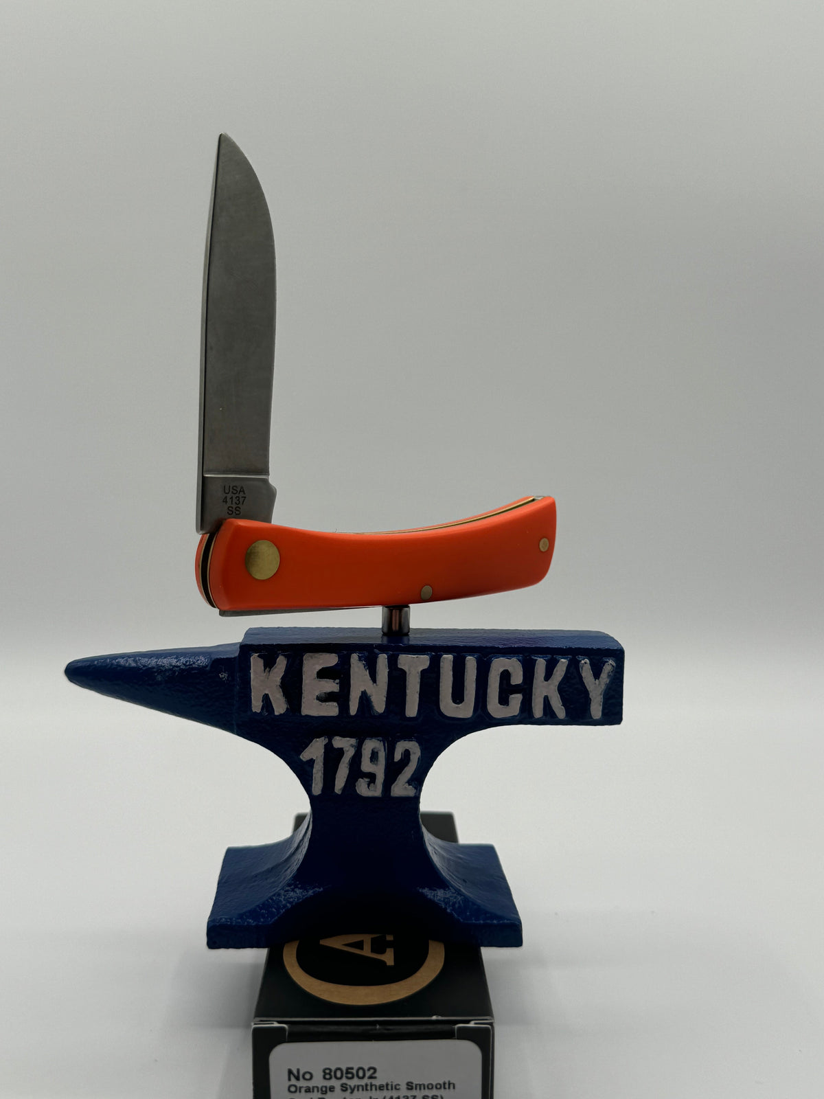 Pigeon Roost Knives Case XX Sod Buster Jr pocket knife with a smooth orange handle displayed on a Kentucky anvil