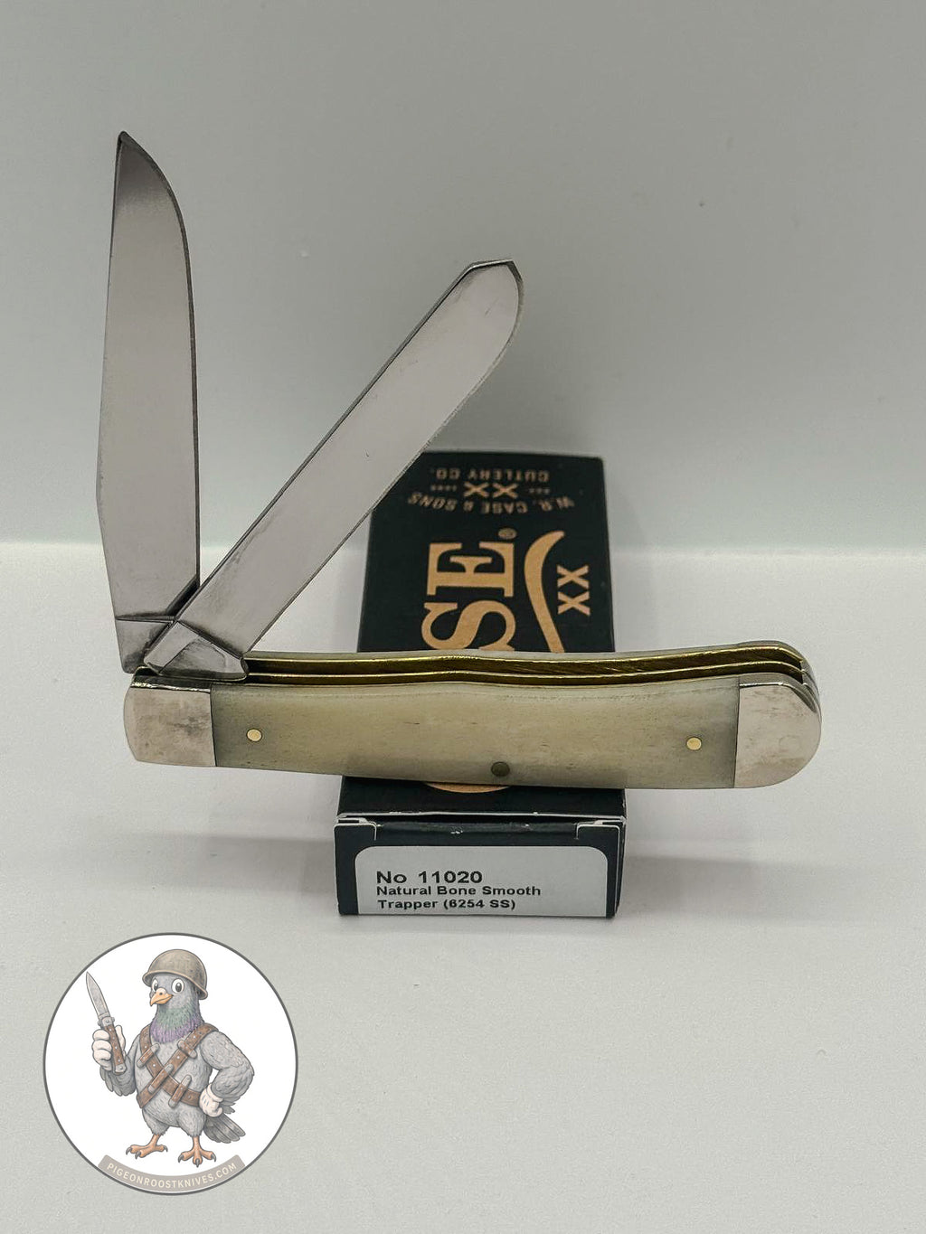 Case XX 11020 Trapper in smooth natural bone with brass shield — angled open view on Case XX packaging
