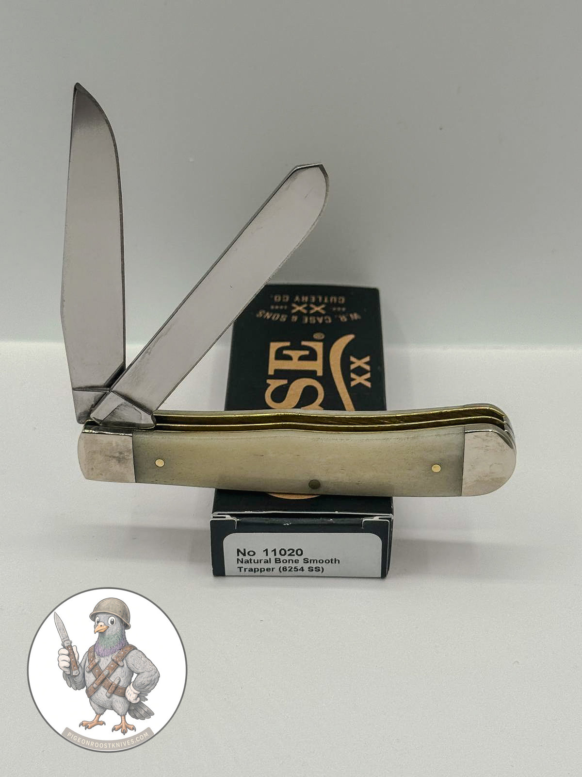 Case XX 11020 Trapper in smooth natural bone with brass shield — angled open view on Case XX packaging