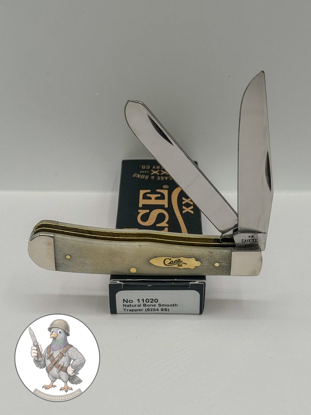 Case XX Trapper with smooth natural bone with brass shield and clip and spey blades, SKU 11020 — blades open resting on the factory box