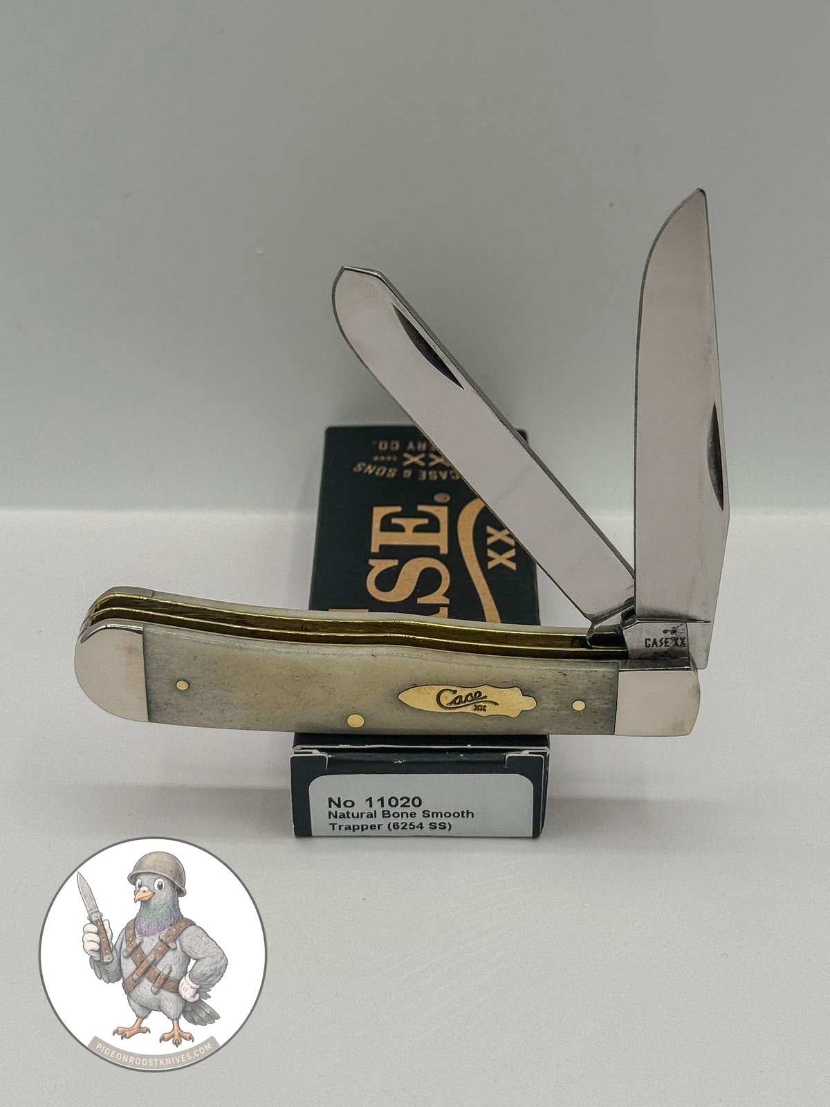 Case XX Trapper with smooth natural bone with brass shield and clip and spey blades, SKU 11020 — blades open resting on the factory box