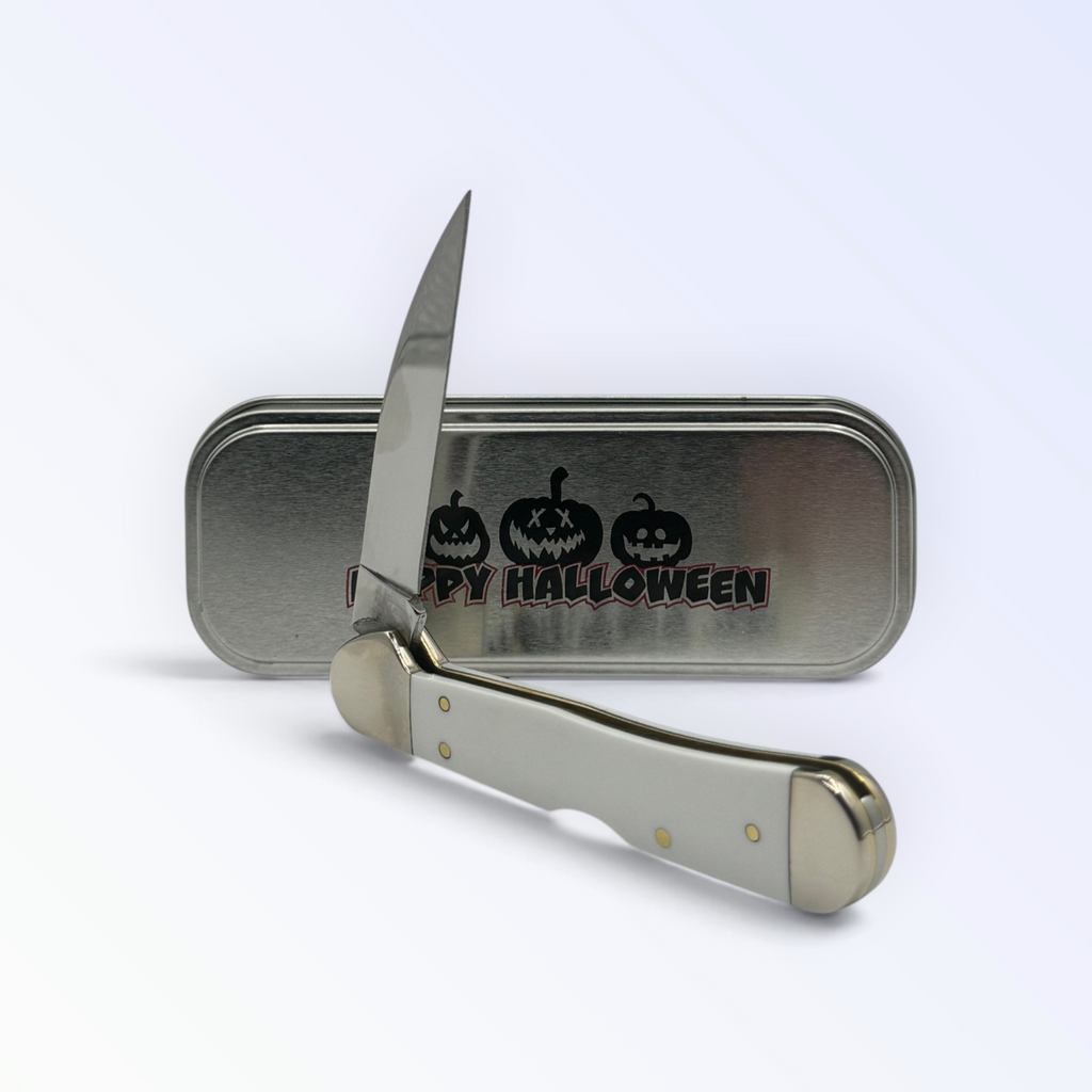 Pigeon Roost Knives Case XX Halloween Copperlock knife with white handle and etched blade in front of collector tin