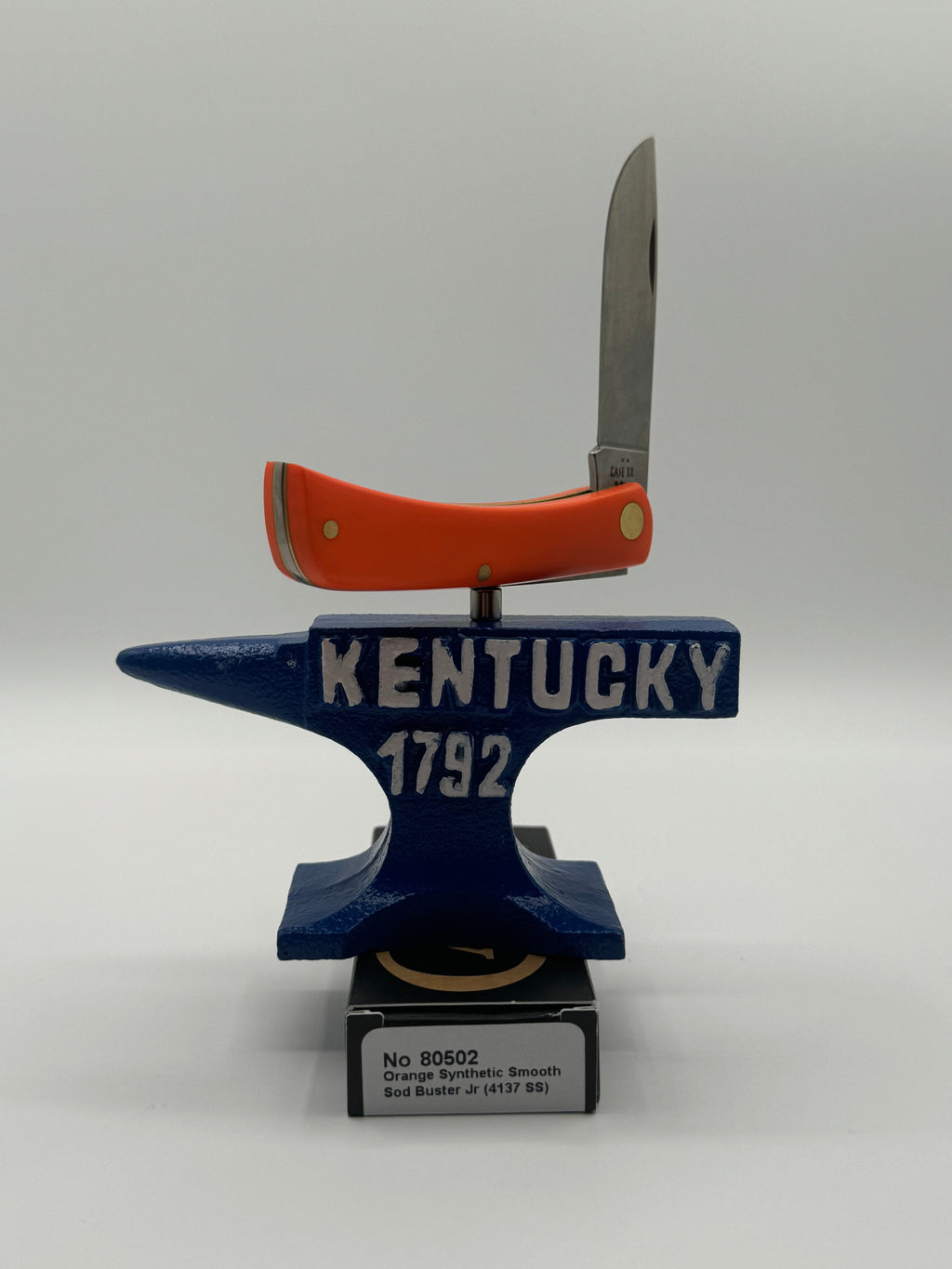 Pigeon Roost Knives Case XX Sod Buster Jr pocket knife with a smooth orange synthetic handle balanced on an anvil