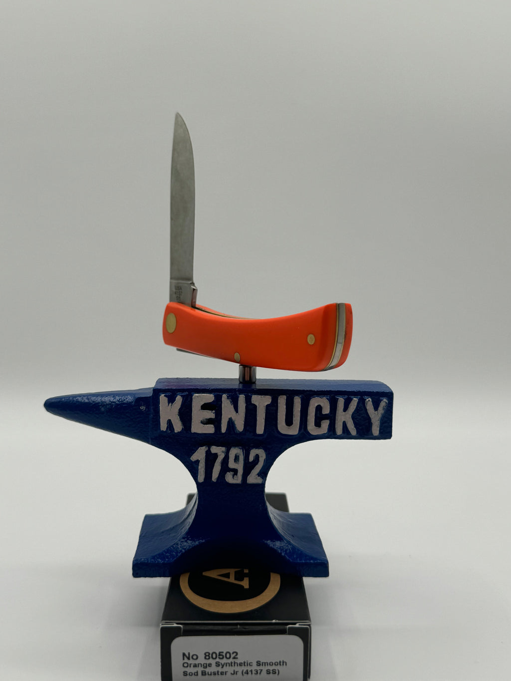Pigeon Roost Knives Case XX Sod Buster Jr pocket knife with a smooth orange synthetic handle resting on an anvil.